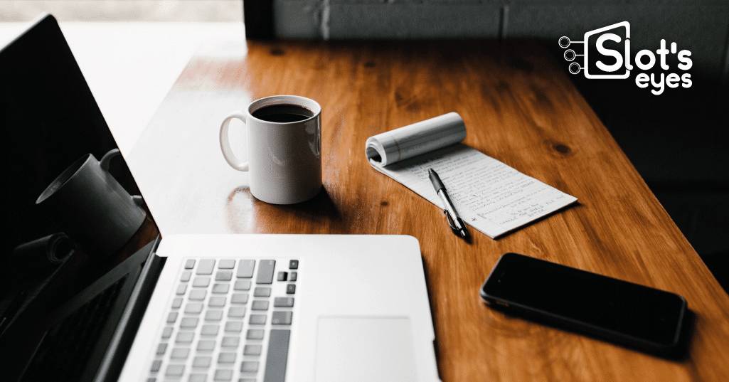 Mesa de trabajo con un portátil, una taza de café, una libreta con anotaciones y un móvil
